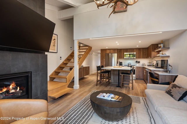 living room with light hardwood / wood-style floors, sink, and a tiled fireplace