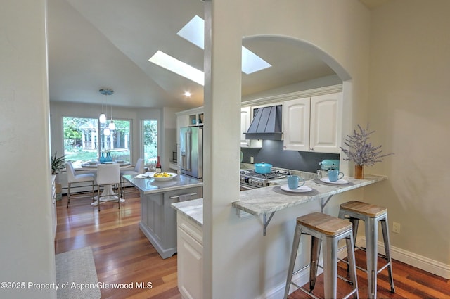 kitchen with custom range hood, stainless steel appliances, white cabinets, light wood-style floors, and lofted ceiling
