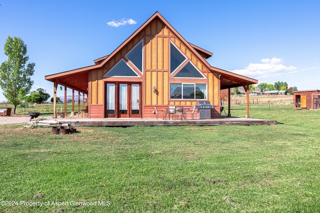 rear view of property featuring a patio area, a yard, an outbuilding, and french doors