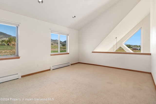 additional living space with a mountain view, a healthy amount of sunlight, lofted ceiling, and a baseboard heating unit