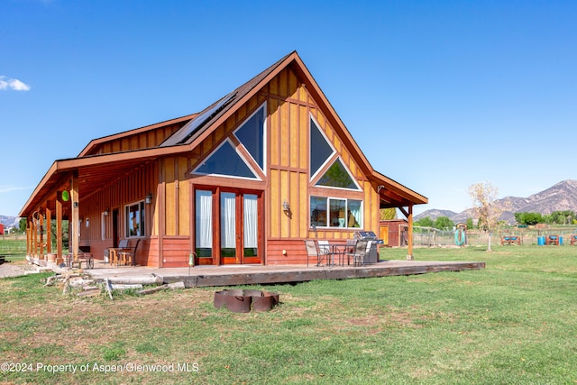 rear view of house featuring a mountain view, a yard, and french doors