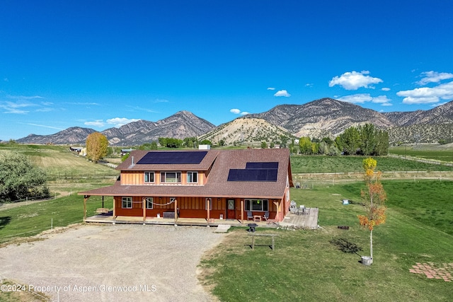 view of front of home featuring solar panels, a deck with mountain view, and a front lawn