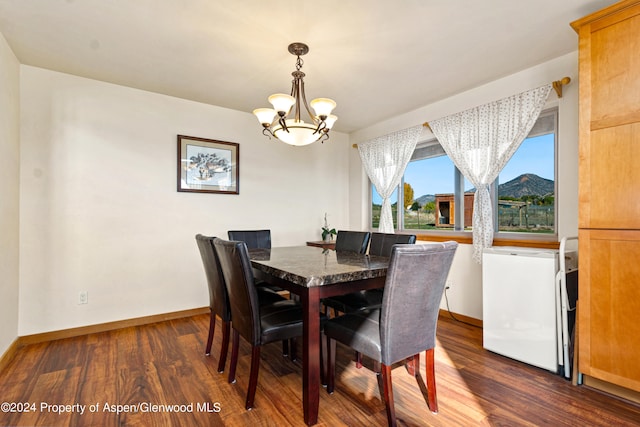 dining space with a mountain view, dark hardwood / wood-style flooring, and an inviting chandelier