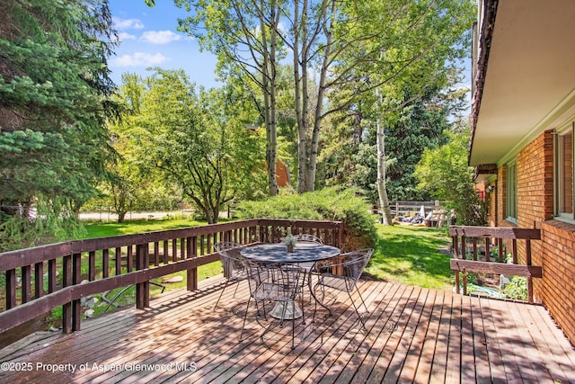 531 Gillespie St, Aspen, CO 81611 - wooden deck with outdoor dining area, a lawn, and view of wooded area