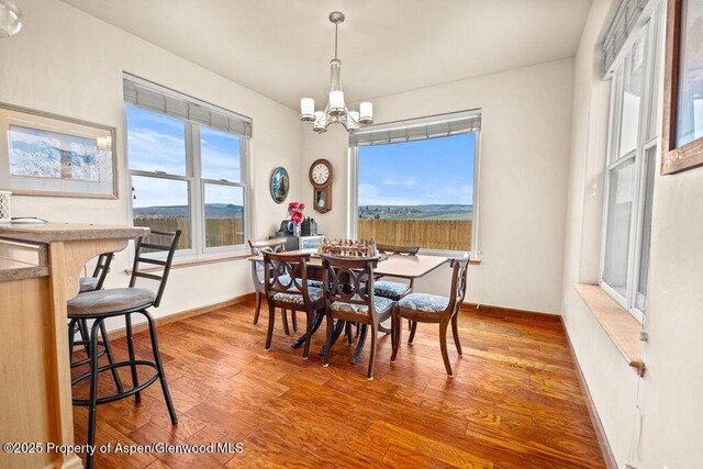 dining space featuring a chandelier, wood finished floors, and baseboards