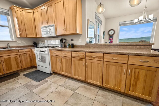 kitchen featuring white appliances, healthy amount of natural light, a sink, and hanging light fixtures