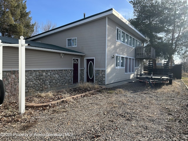 back of property featuring stone siding and driveway