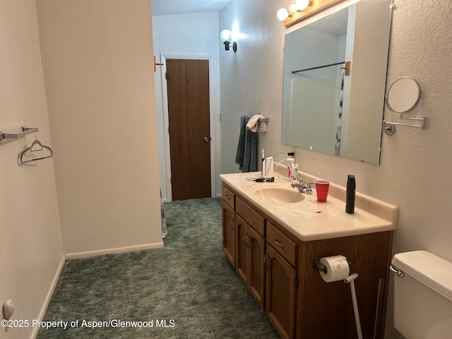 bathroom featuring baseboards, toilet, and vanity