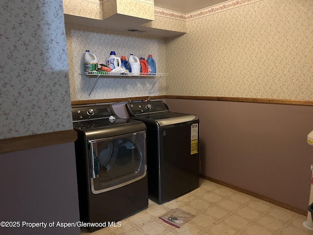 clothes washing area with wallpapered walls, light floors, laundry area, wainscoting, and independent washer and dryer