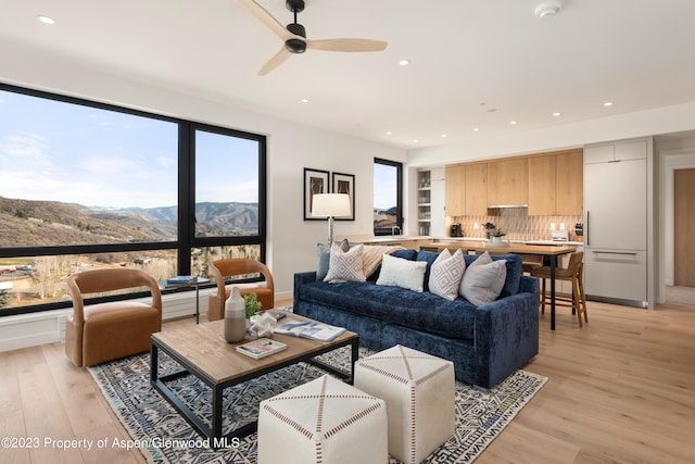 living room featuring a mountain view, light hardwood / wood-style flooring, and ceiling fan