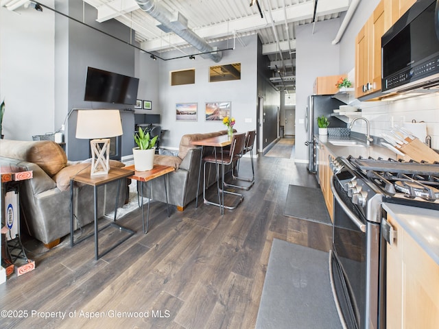 231 Robinson St Unit R306, Basalt, CO 81621 - kitchen with stainless steel range with gas cooktop, open floor plan, dark wood finished floors, light brown cabinets, and a high ceiling