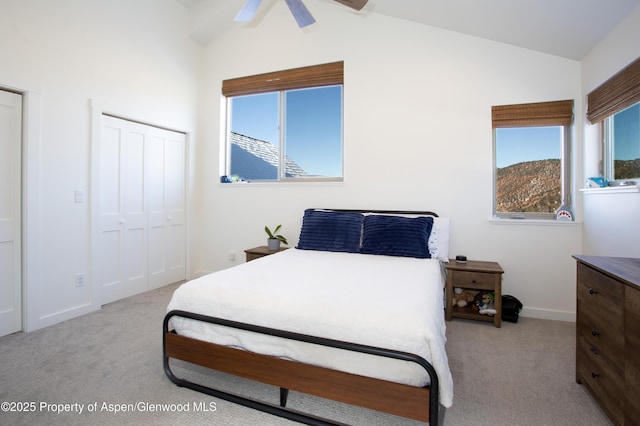 bedroom featuring lofted ceiling, a closet, ceiling fan, and light colored carpet