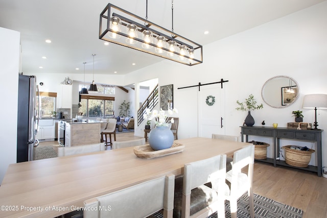 dining space featuring light wood-type flooring and a barn door