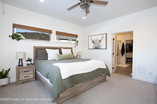 bedroom with light colored carpet, a closet, ceiling fan, and a spacious closet