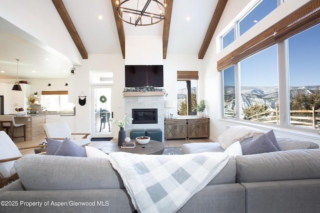 living room with a fireplace, a chandelier, lofted ceiling with beams, and wood-type flooring