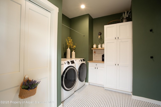 laundry room featuring separate washer and dryer and cabinets