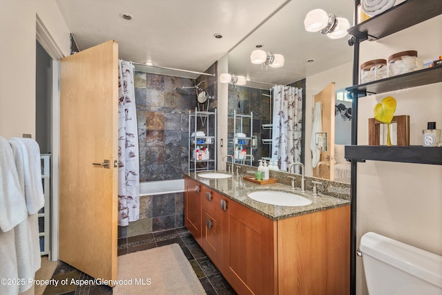 bathroom featuring double vanity, toilet, tiled shower / bath combo, and a sink