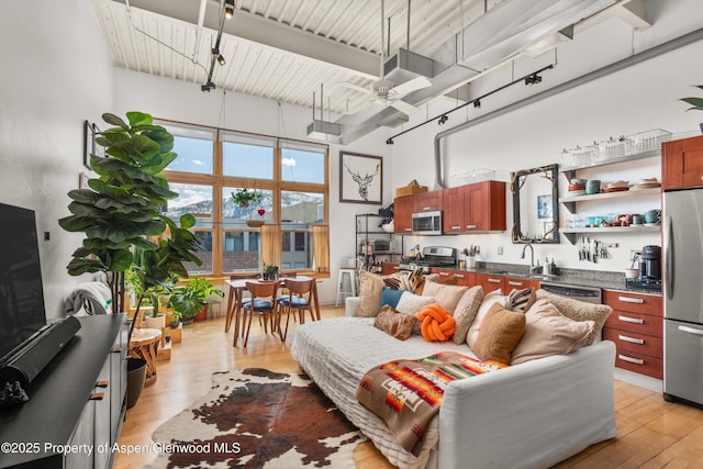 living room featuring light wood-style floors, a high ceiling, and ceiling fan