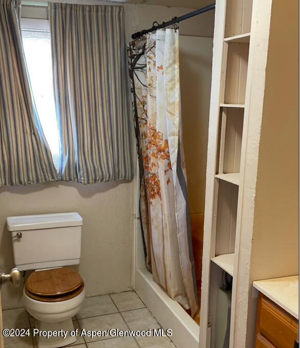 bathroom featuring a shower with curtain, tile patterned flooring, vanity, and toilet