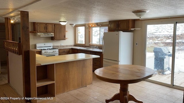 kitchen featuring sink, white appliances, kitchen peninsula, and light tile patterned floors