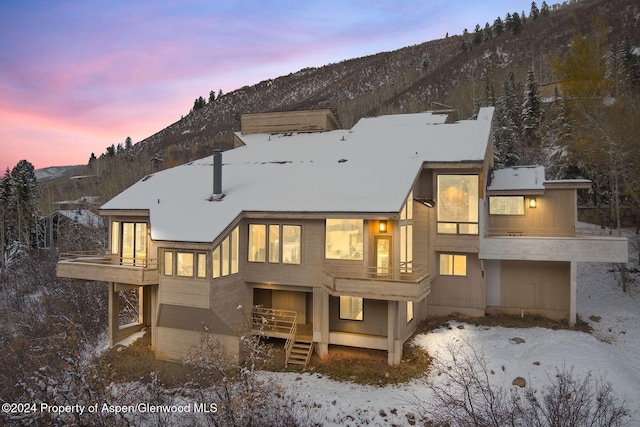 snow covered house with a mountain view and a balcony