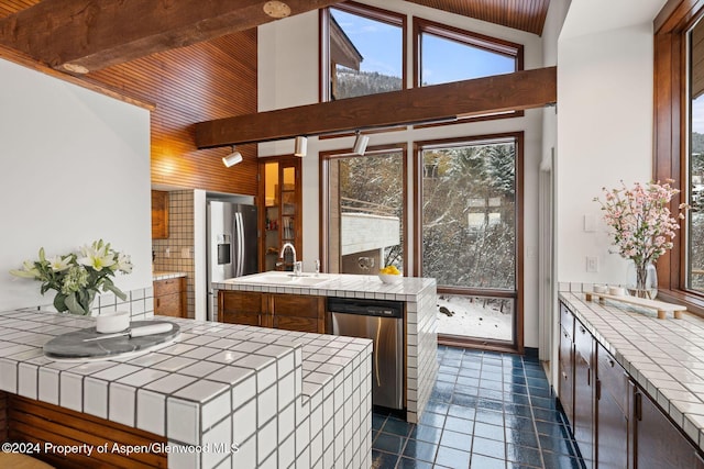 kitchen with tile countertops, sink, a center island with sink, and stainless steel appliances