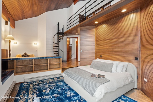 bedroom featuring a baseboard heating unit, wooden walls, and wood ceiling