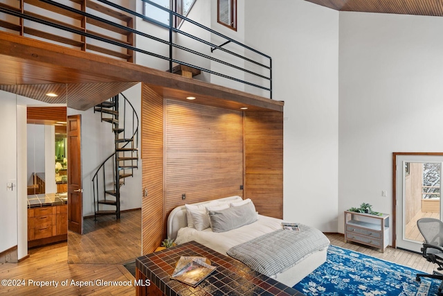 bedroom with a towering ceiling, hardwood / wood-style flooring, and wooden ceiling