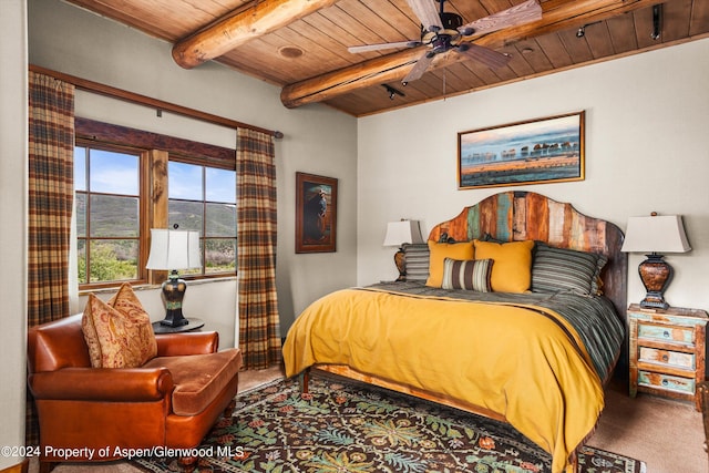 carpeted bedroom with ceiling fan, beamed ceiling, and wood ceiling