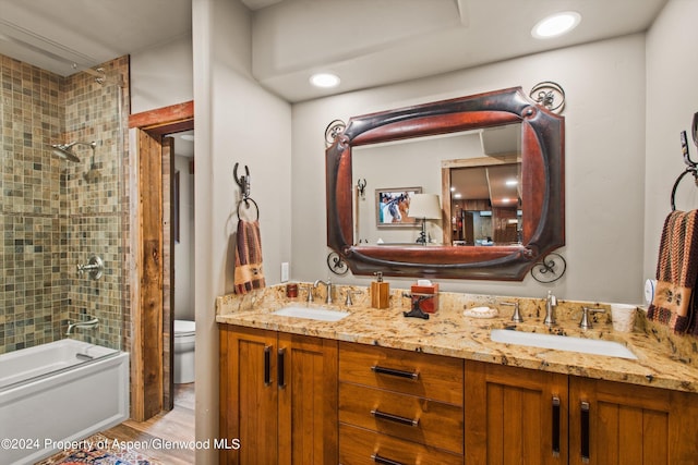 full bathroom featuring vanity, tiled shower / bath, and toilet