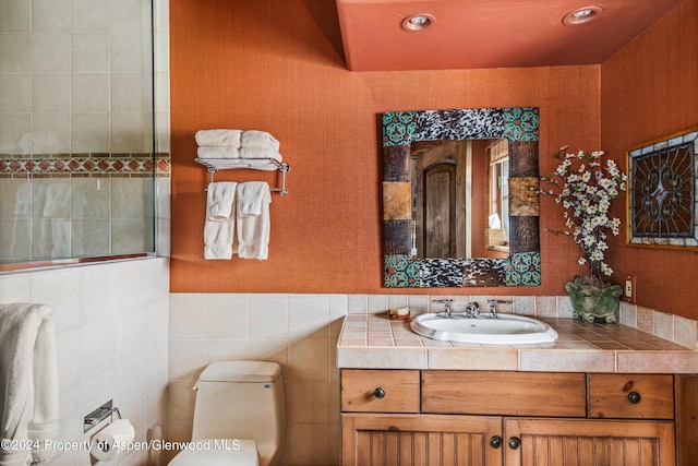 bathroom with vanity, toilet, and tile walls