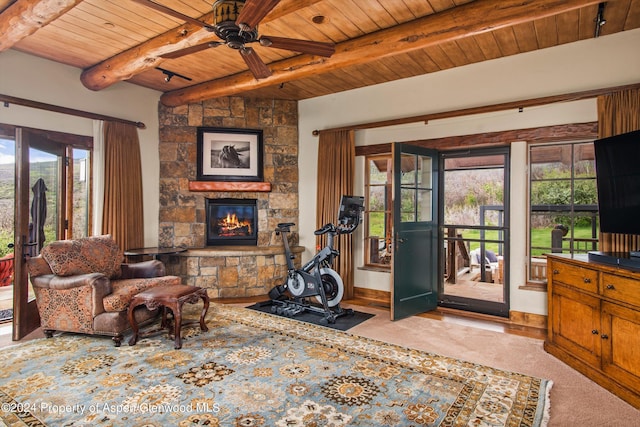 interior space featuring ceiling fan, beam ceiling, a stone fireplace, and wooden ceiling