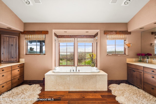 bathroom with vanity, hardwood / wood-style flooring, and tiled tub