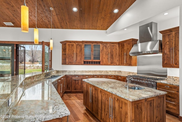 199 Bluestem Ct, Carbondale, CO 81623 - kitchen featuring light stone countertops, wall chimney exhaust hood, sink, decorative light fixtures, and a center island with sink