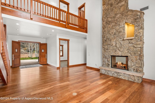 199 Bluestem Ct, Carbondale, CO 81623 - unfurnished living room with hardwood / wood-style flooring, a stone fireplace, and a high ceiling