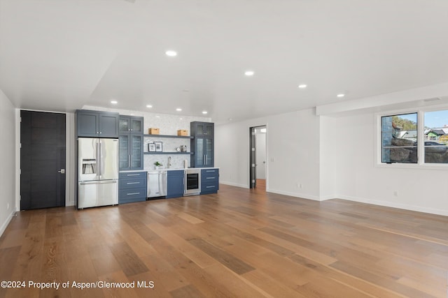 kitchen with backsplash, sink, wine cooler, light hardwood / wood-style floors, and stainless steel appliances