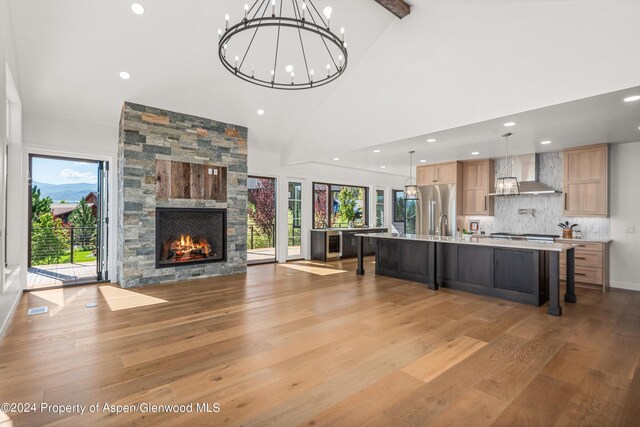 unfurnished living room with a fireplace, beam ceiling, high vaulted ceiling, and hardwood / wood-style floors