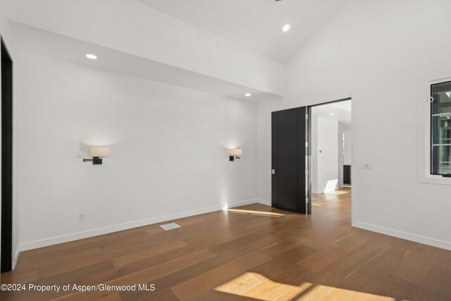 empty room with wood-type flooring and high vaulted ceiling