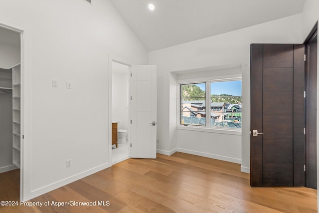 unfurnished bedroom with wood-type flooring, vaulted ceiling, and ensuite bath