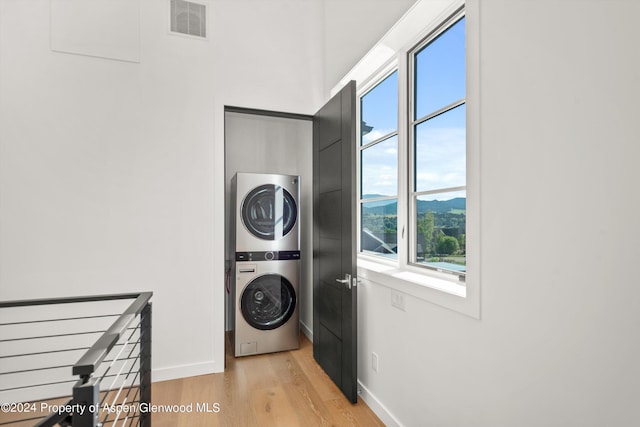 laundry area with a mountain view, light wood-type flooring, and stacked washing maching and dryer