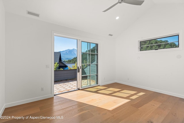 spare room with hardwood / wood-style floors, a mountain view, ceiling fan, and vaulted ceiling