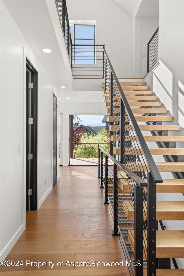 stairs with hardwood / wood-style flooring and a high ceiling