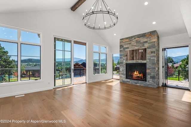 unfurnished living room with a mountain view, beam ceiling, a wealth of natural light, and a fireplace