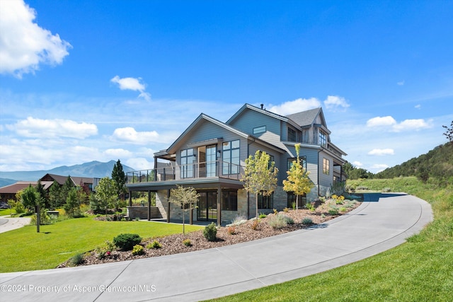 view of front of house featuring a mountain view, a balcony, and a front yard