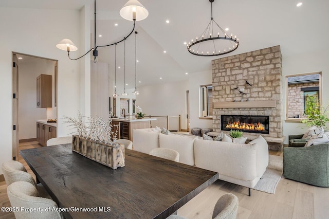 112 Bowles Dr, Carbondale, CO 81623 - dining room featuring high vaulted ceiling, light wood-style flooring, a chandelier, a fireplace, and wine cooler