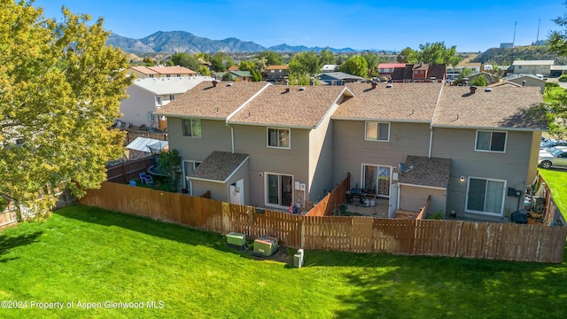 rear view of house featuring a mountain view and a yard