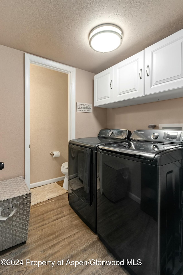 laundry area featuring washer and clothes dryer, wood-type flooring, and a textured ceiling