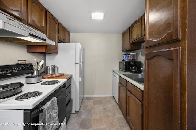 693 N 7th St, Silt, CO 81652 - kitchen with white appliances, under cabinet range hood, a sink, light countertops, and baseboards