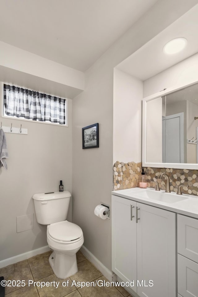 bathroom with decorative backsplash, toilet, vanity, tile patterned flooring, and baseboards