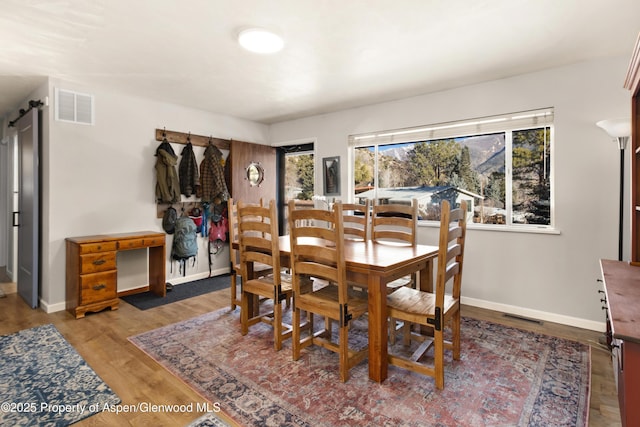 dining room featuring wood finished floors, visible vents, and baseboards